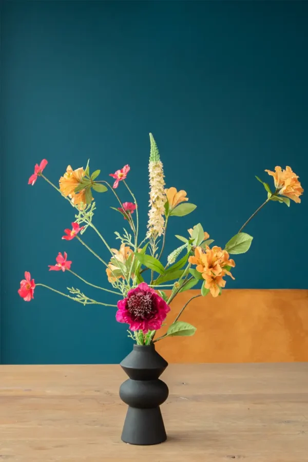 Jula Bloom’s Coco silk flower bouquet with orange, yellow and pink blooms, in a black vase