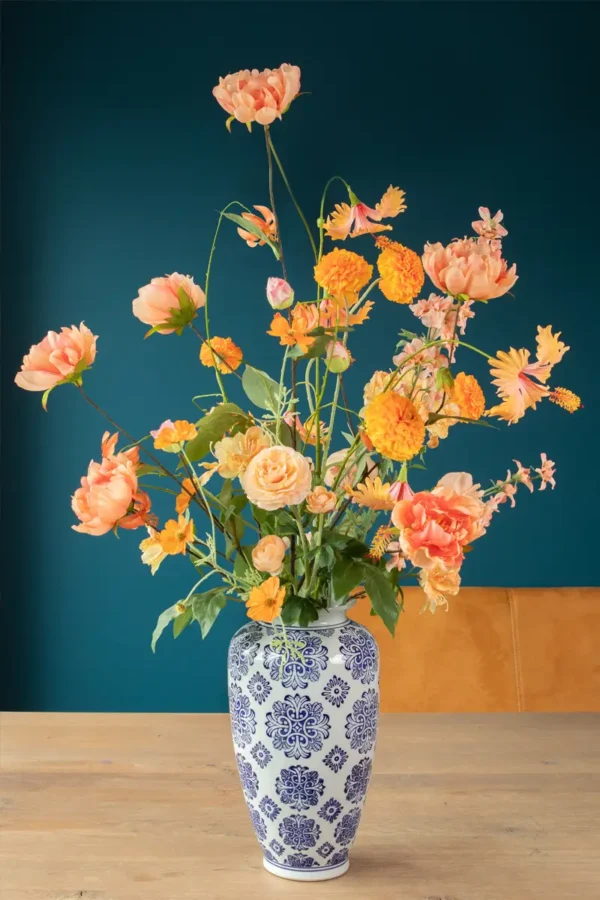 Jula Bloom’s Curie silk flower bouquet with peach and orange blooms, in a traditional white and blue painted vase