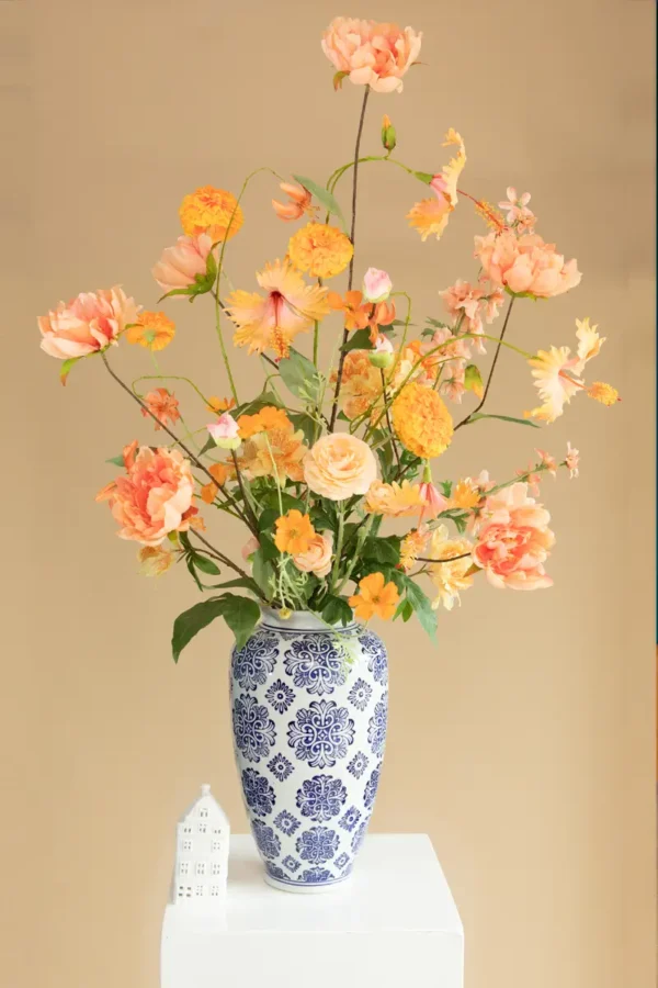 Jula Bloom’s Curie silk flower bouquet with peach and orange blooms, in a traditional white and blue painted vase