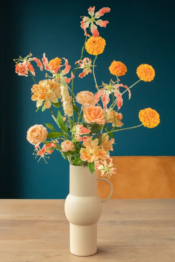 Jula Bloom’s Arc silk flower bouquet with orange and peach blooms, in a white vase with handle