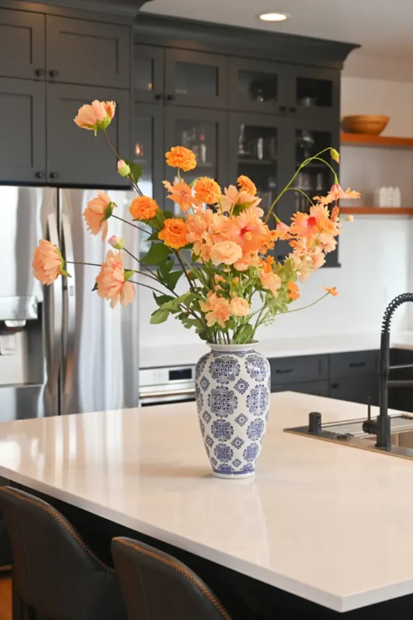 Jula Bloom’s Curie silk flower bouquet with orange blooms in blue and white vase on a kitchen counter