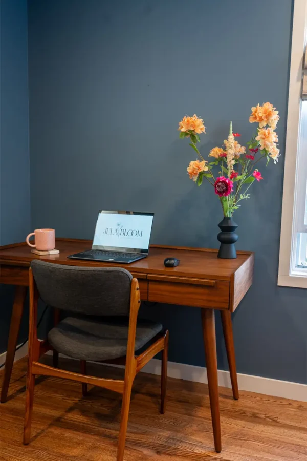 Jula Bloom’s Coco silk flower bouquet with pink and orange blooms in black vase on a wooden desk