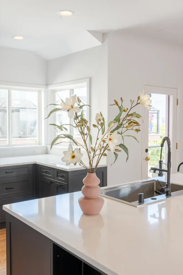 Jula Bloom’s Nightingale silk flower bouquet with large white blooms, in a light pink vase on a kitchen counter top