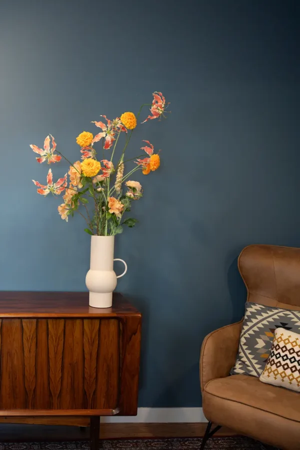 Jula Bloom’s Ginsbury silk flower bouquet with pink and orange blooms in a white vase, placed on a wooden counter