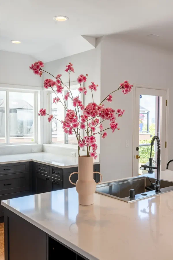 Jula Bloom’s Yosano silk flower bouquet with pink blooms in a white vase, on a kitchen counter