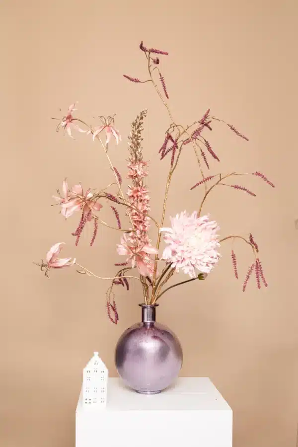 Jula Bloom’s Meitner silk flower bouquet with pink blooms, gold thistles and green leaf, in a violet sheen vase, on a white pillar